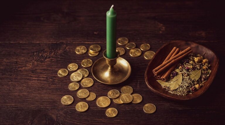 A green candle surrounded by coins and a small dish of herbs on a wooden altar, ready for a money visualization ritual